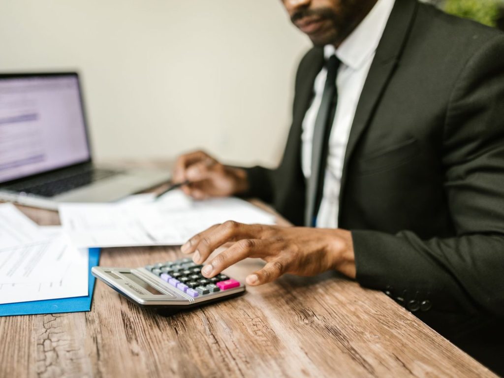 Accountant in a suit using a calculator beside financial documents