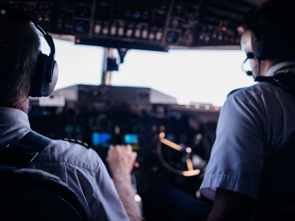 Two airline pilots in uniform and headsets on the flight deck