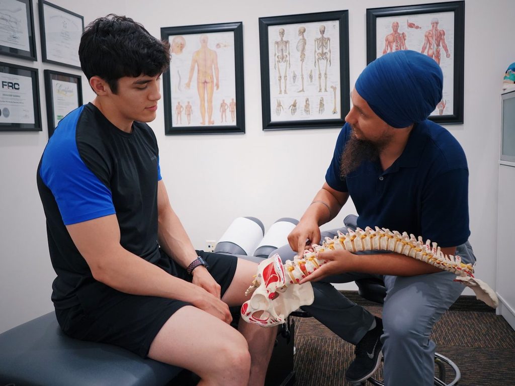 A chiropractor explaining the spine to a patient with a spine model