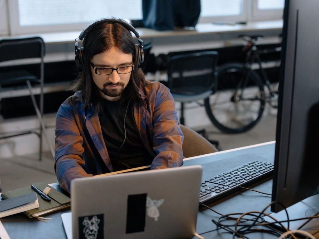 Developer in headphones working on a laptop in an open office
