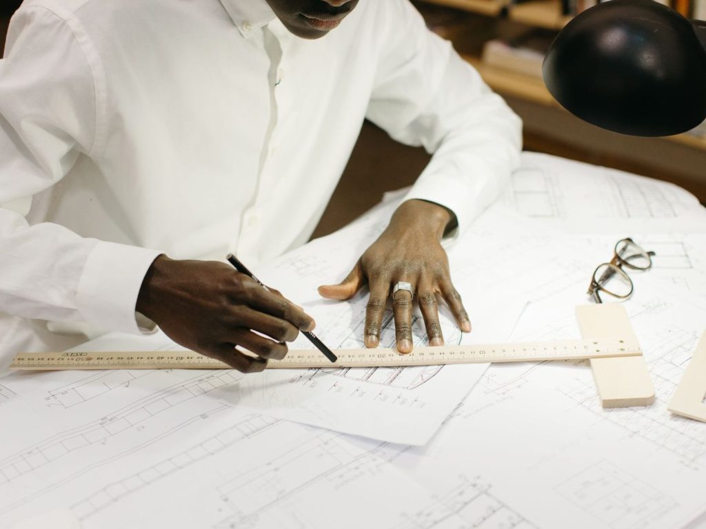 Engineer drawing on blueprints at an office desk