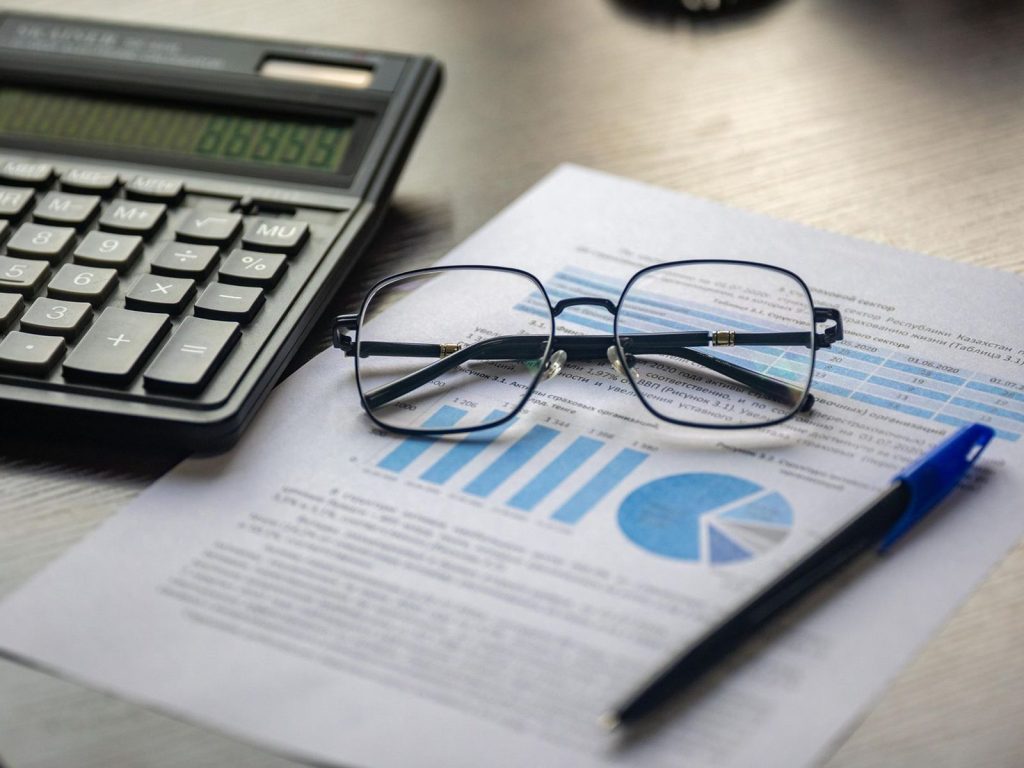 Financial report with a calculator, pen and glasses