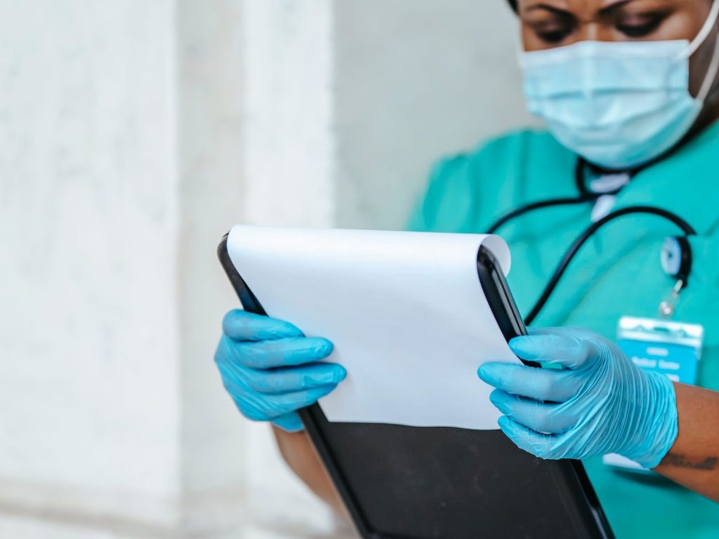 A nurse reviewing a chart on a clipboard in a hospital hallway