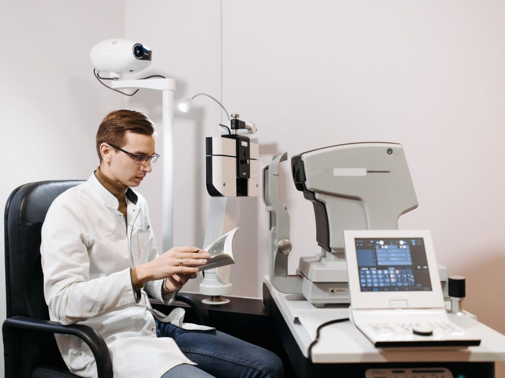 An eye care professional in an exam room with diagnostic equipment